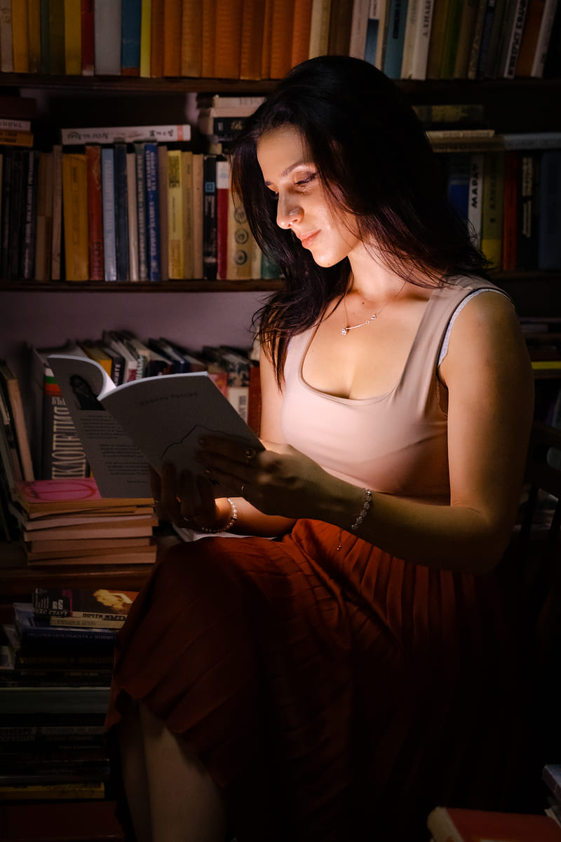 Жена чете книга, огряна от топла светлина